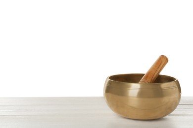 Golden singing bowl and mallet on wooden table against white background, space for text