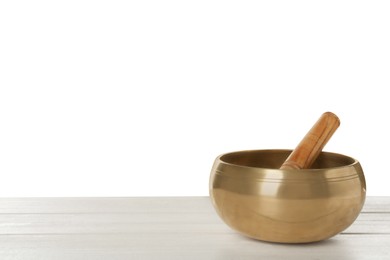 Photo of Golden singing bowl and mallet on wooden table against white background, space for text