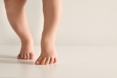 Photo of Little baby on light background, closeup on feet. Space for text