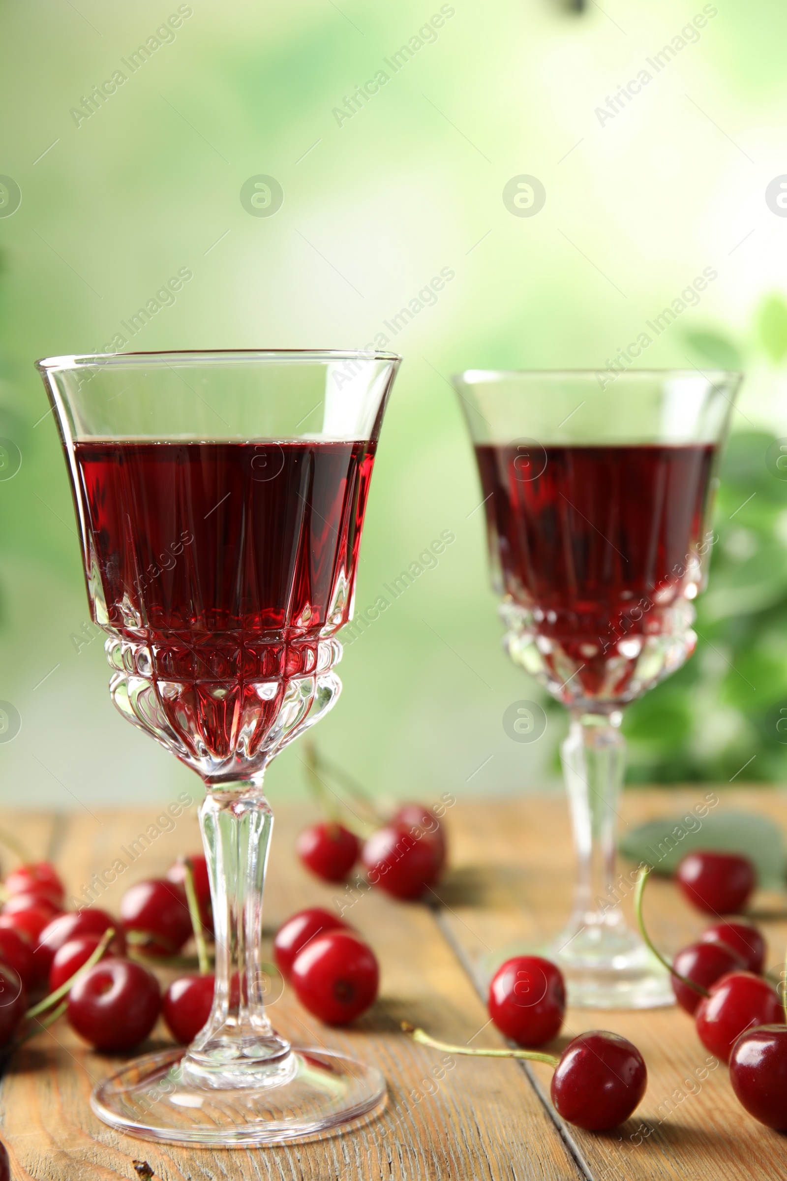 Photo of Delicious cherry wine with ripe juicy berries on wooden table