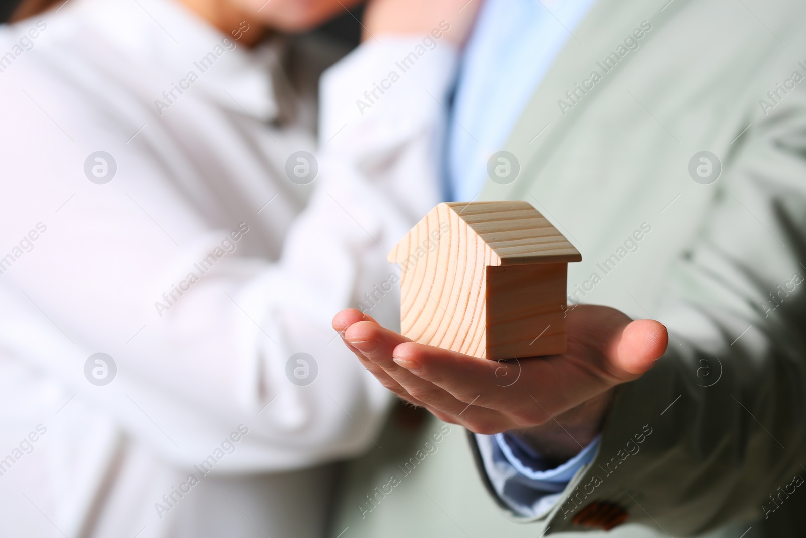 Photo of Young couple holding house figure, closeup. Home insurance