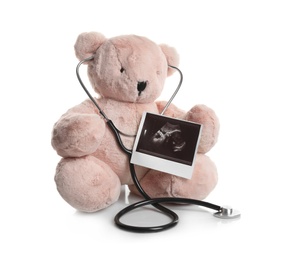 Photo of Ultrasound photo of baby and toy teddy bear on white background. Concept of pregnancy