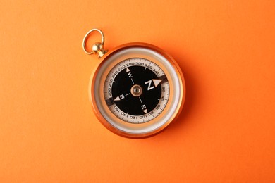 Photo of One compass on orange background, top view