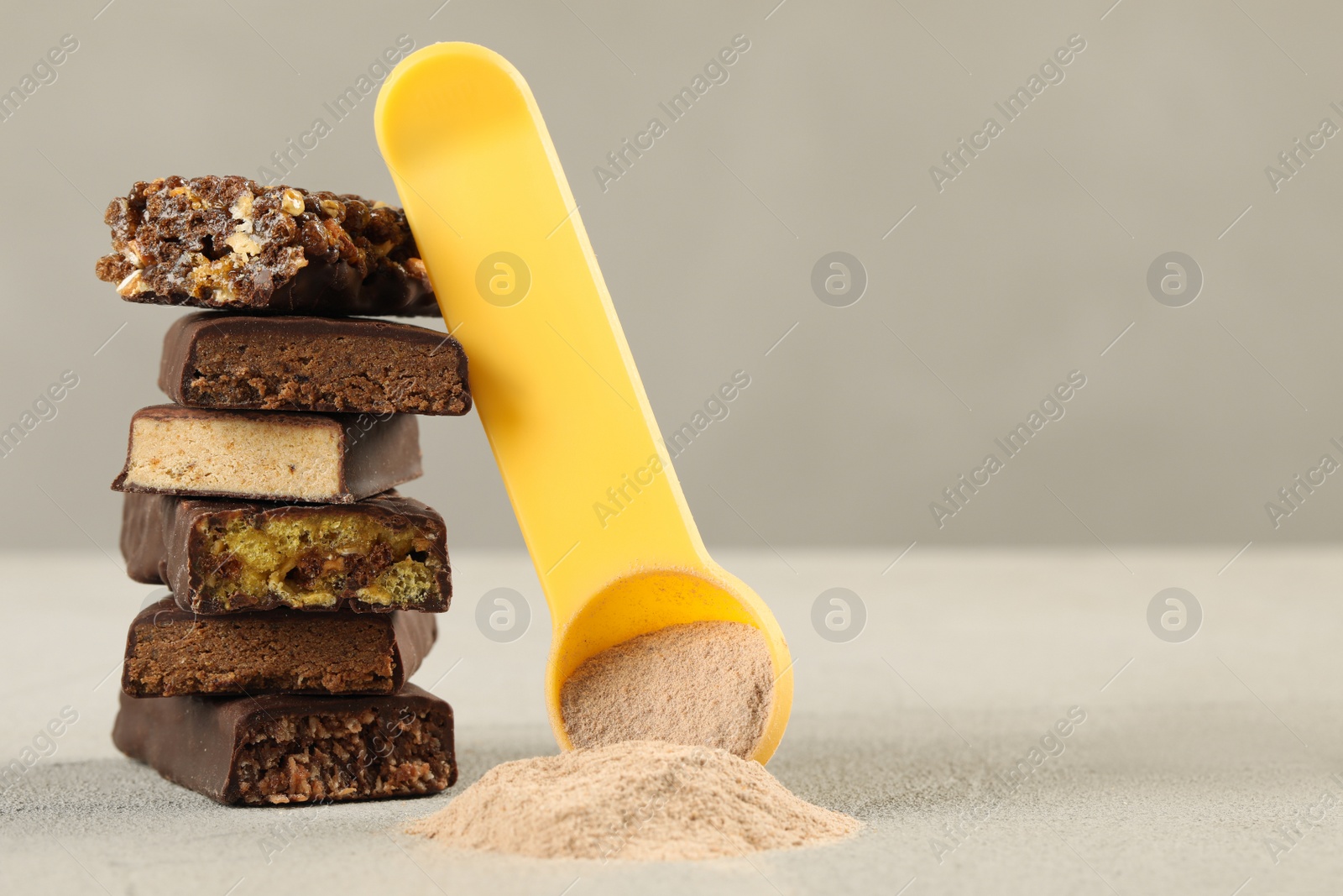 Photo of Different tasty energy bars and protein powder on light table, space for text