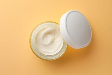 Jar of face cream on beige background, top view