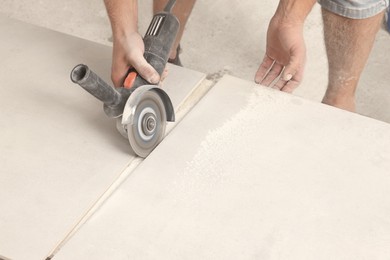 Worker cutting tiles with circular saw indoors, closeup