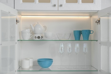 Open kitchen cabinet with different clean dishware