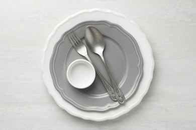 Photo of Stylish setting with cutlery, bowl and plates on light textured table, top view