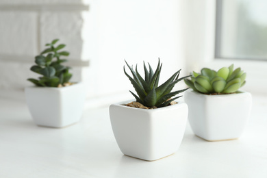 Beautiful artificial plants in flower pots on window sill