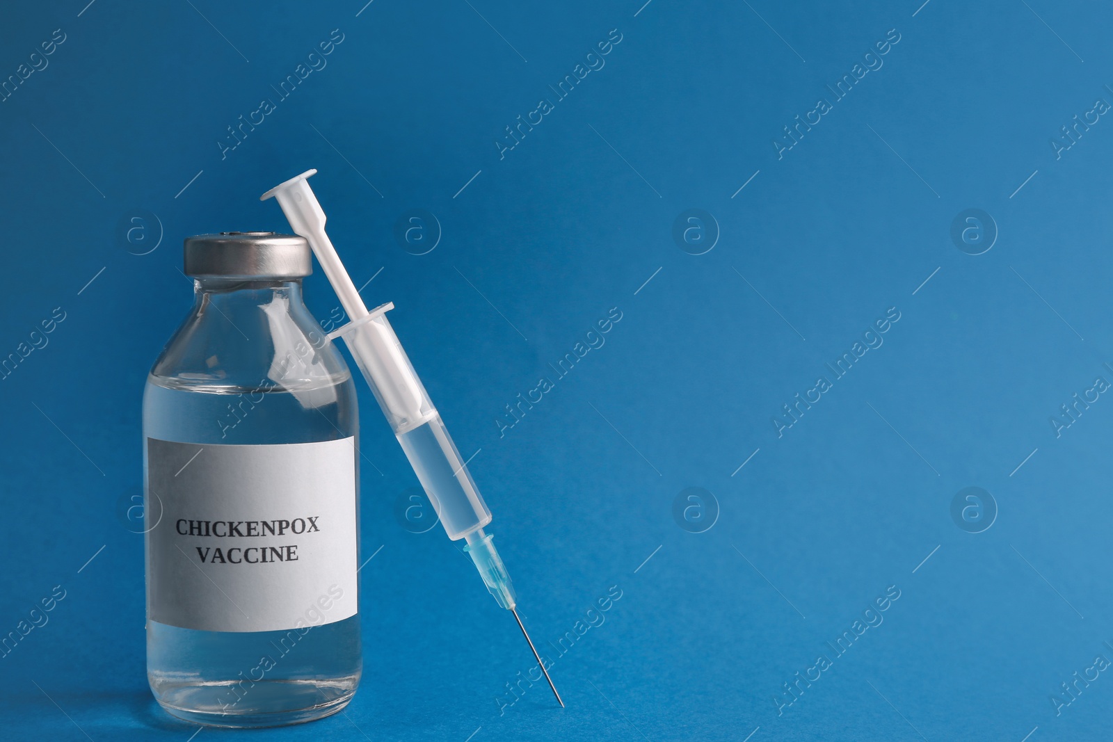 Photo of Chickenpox vaccine and syringe on blue background, space for text. Varicella virus prevention