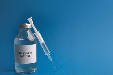 Photo of Chickenpox vaccine and syringe on blue background, space for text. Varicella virus prevention
