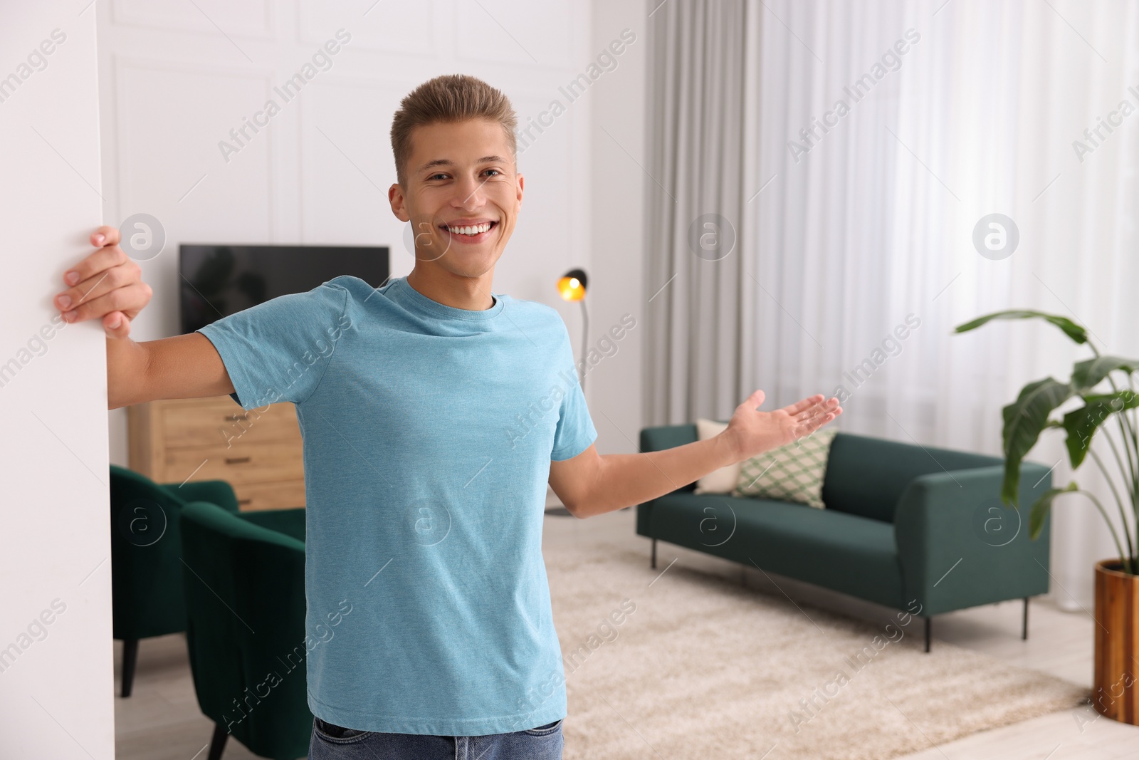 Photo of Happy man welcoming near white wall at home, space for text. Invitation to come in room