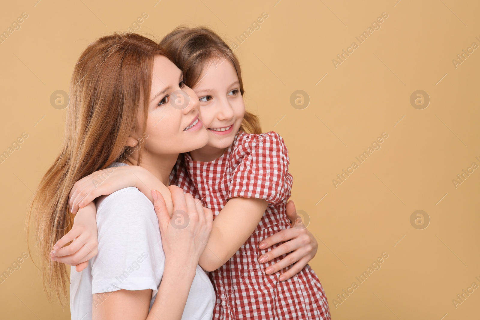 Photo of Portrait of mother and her cute daughter on beige background. Space for text