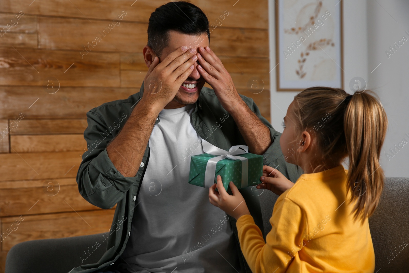 Photo of Man receiving gift for Father's Day from his daughter at home