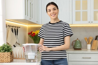 Woman with filter jug of water in kitchen