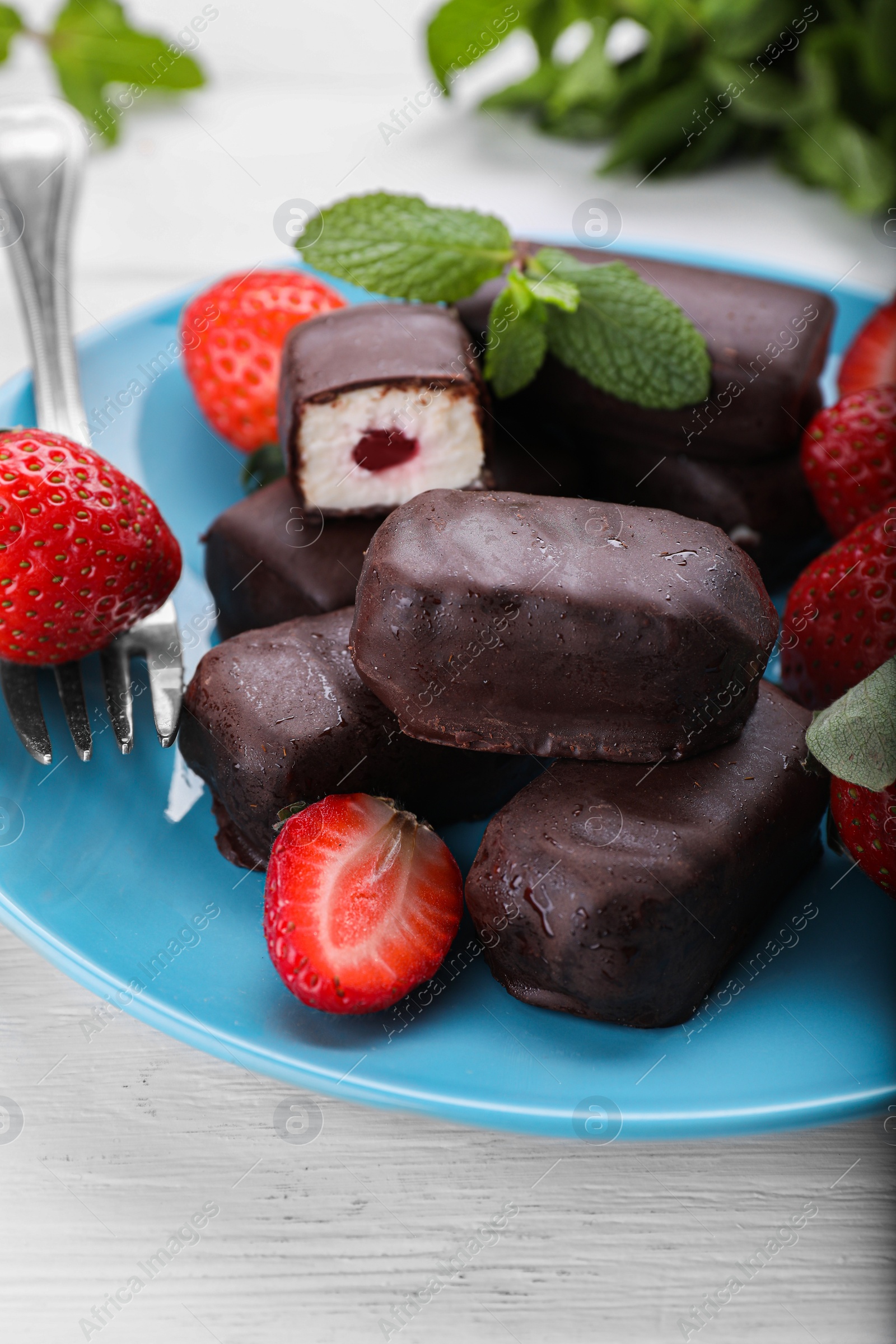 Photo of Delicious glazed curd snacks and fresh strawberries on white wooden table, closeup