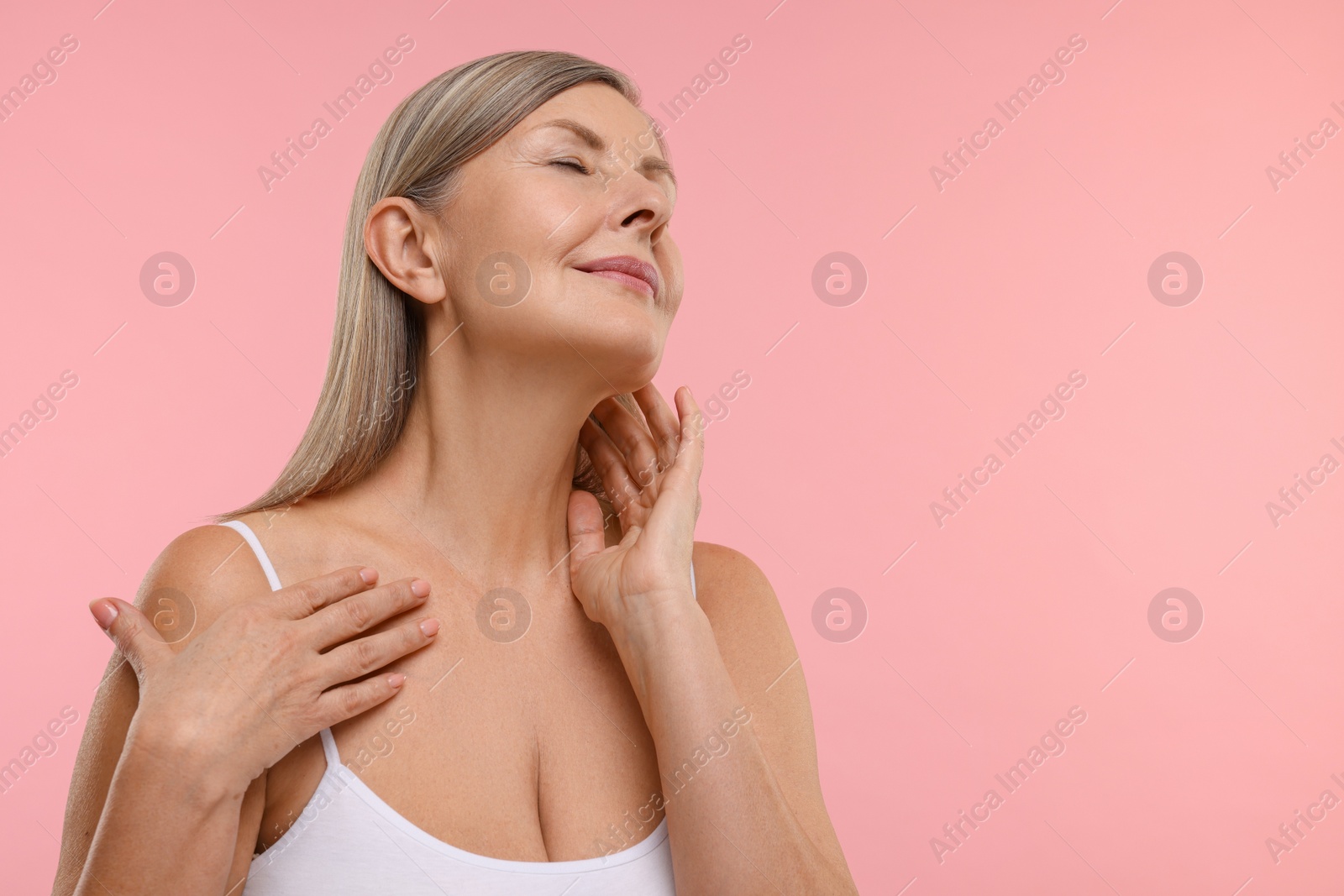 Photo of Beautiful woman touching her neck on pink background, space for text