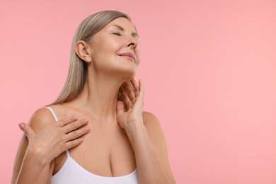 Photo of Beautiful woman touching her neck on pink background, space for text