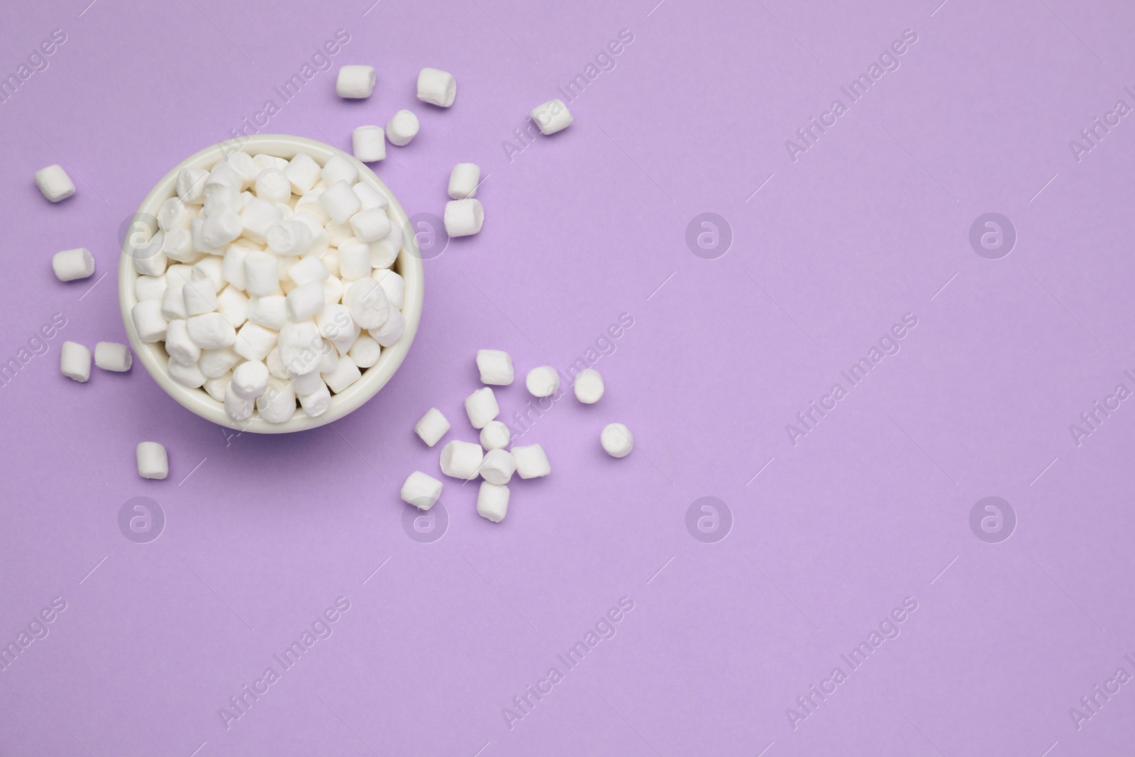 Photo of Delicious sweet marshmallows with bowl on purple background, flat lay. Space for text