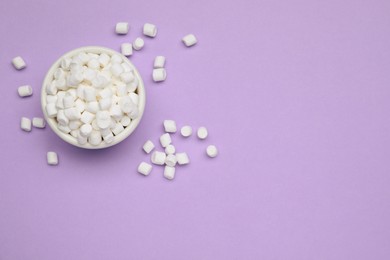 Photo of Delicious sweet marshmallows with bowl on purple background, flat lay. Space for text