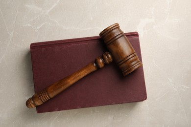 Photo of Wooden gavel and book on light textured table, top view