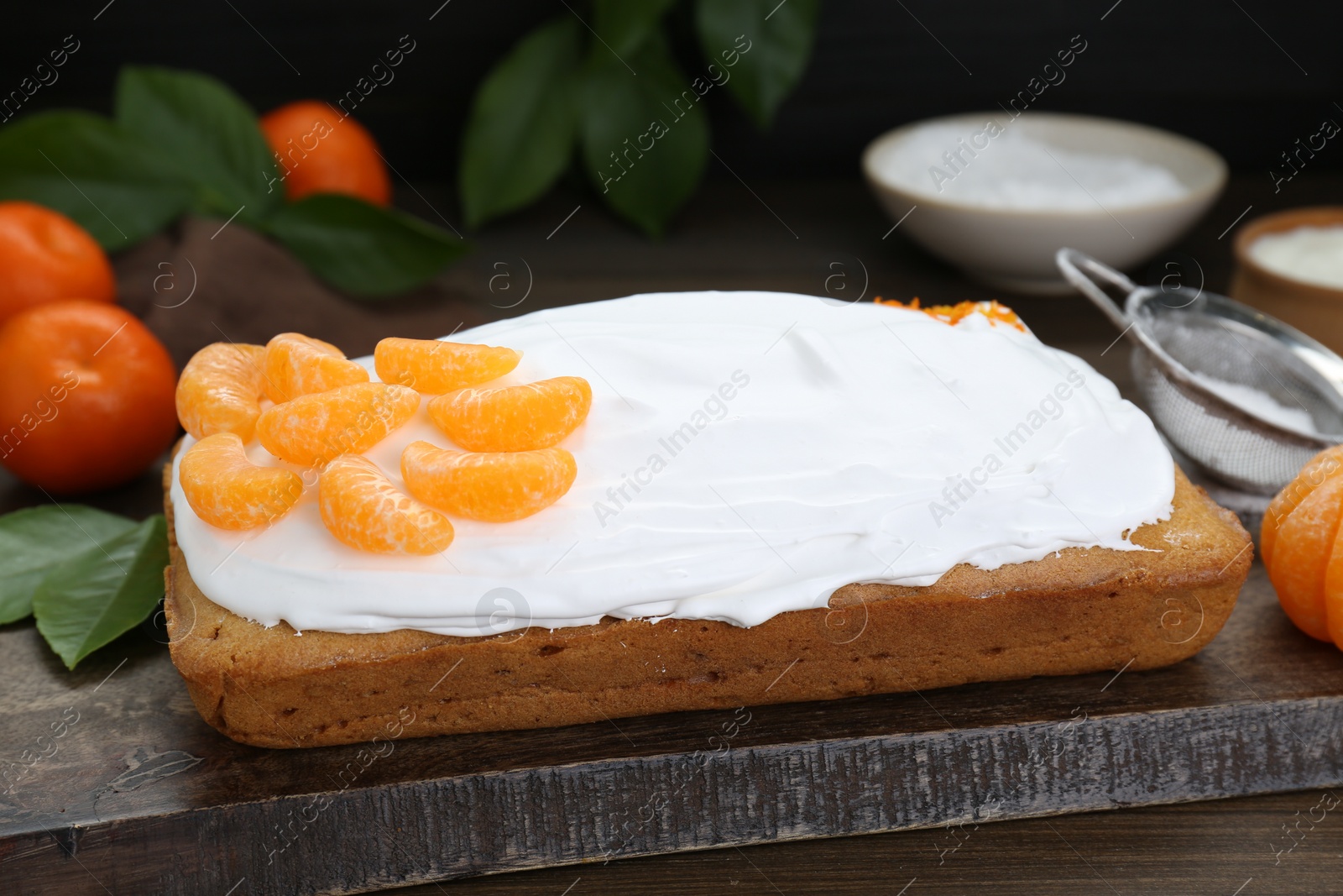 Photo of Delicious homemade yogurt cake with tangerines and cream on wooden table, closeup