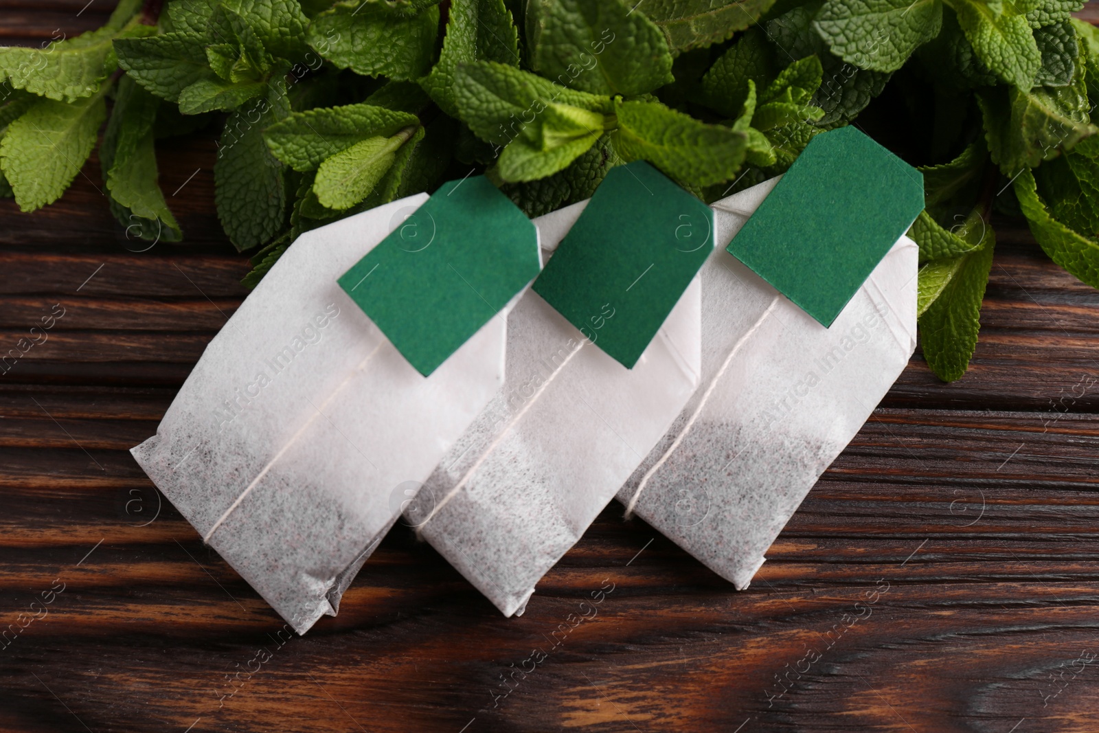 Photo of Tea bags and mint on wooden table, top view