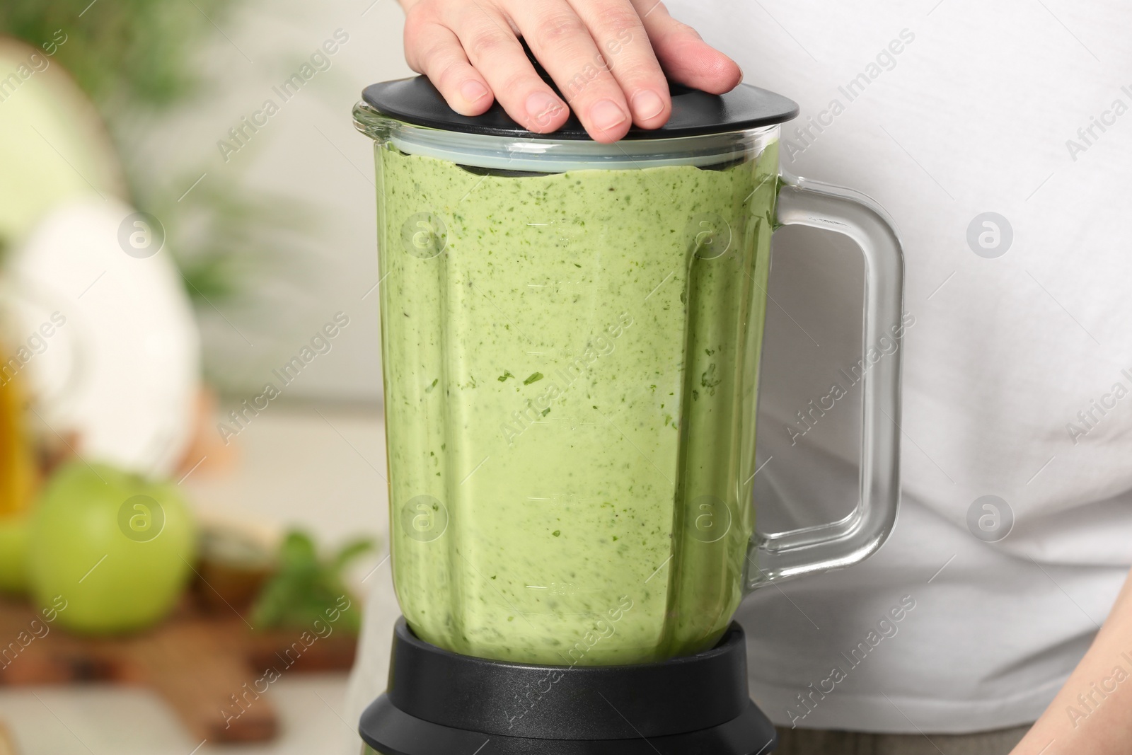 Photo of Woman preparing tasty green smoothie in kitchen, closeup