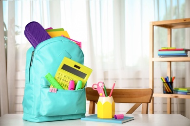 Photo of Bright backpack and school stationery on table indoors, space for text