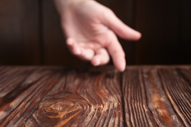 Woman holding hand above wooden table, selective focus. Space for text