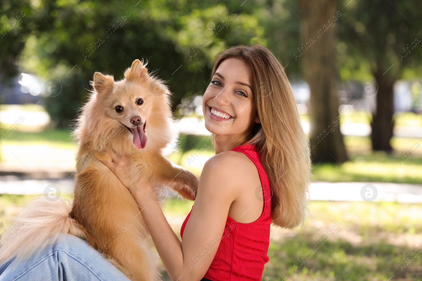 Photo of Young woman with her cute dog in park on sunny day