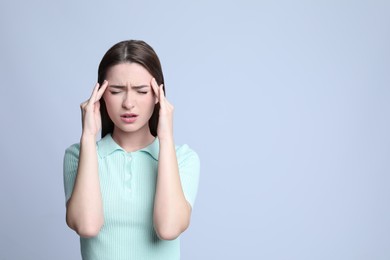 Photo of Young woman suffering from headache on light background, space for text