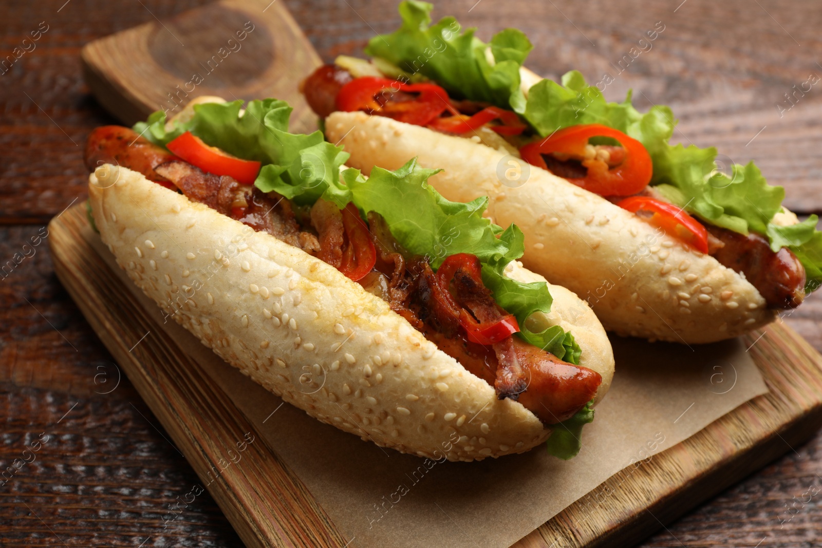 Photo of Tasty hot dogs on wooden table, closeup. Fast food