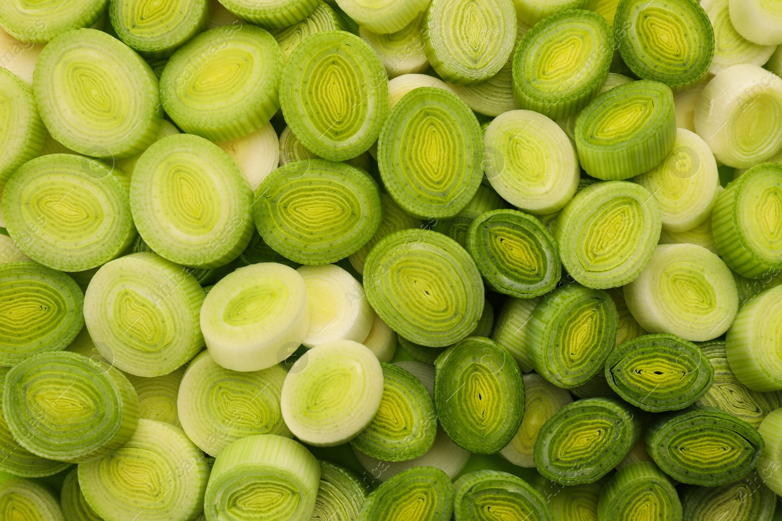 Photo of Fresh raw leek slices as background, top view