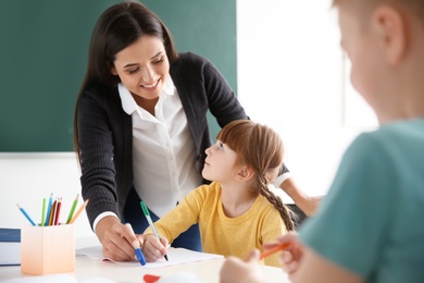 Female teacher helping girl with her task in classroom at school