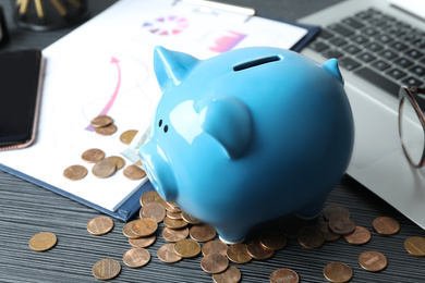 Piggy bank and money on grey wooden table, closeup