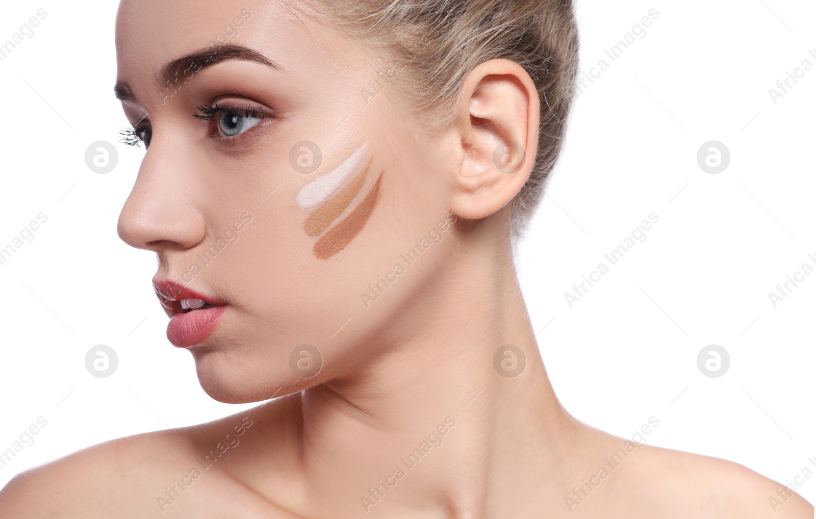 Photo of Young woman with different shades of skin foundation on her face against white background. Professional makeup