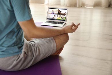 Distance yoga course during coronavirus pandemic. Man having online video class via laptop at home, closeup