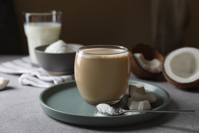 Glass of coffee with coconut milk, pieces and flakes on light grey table