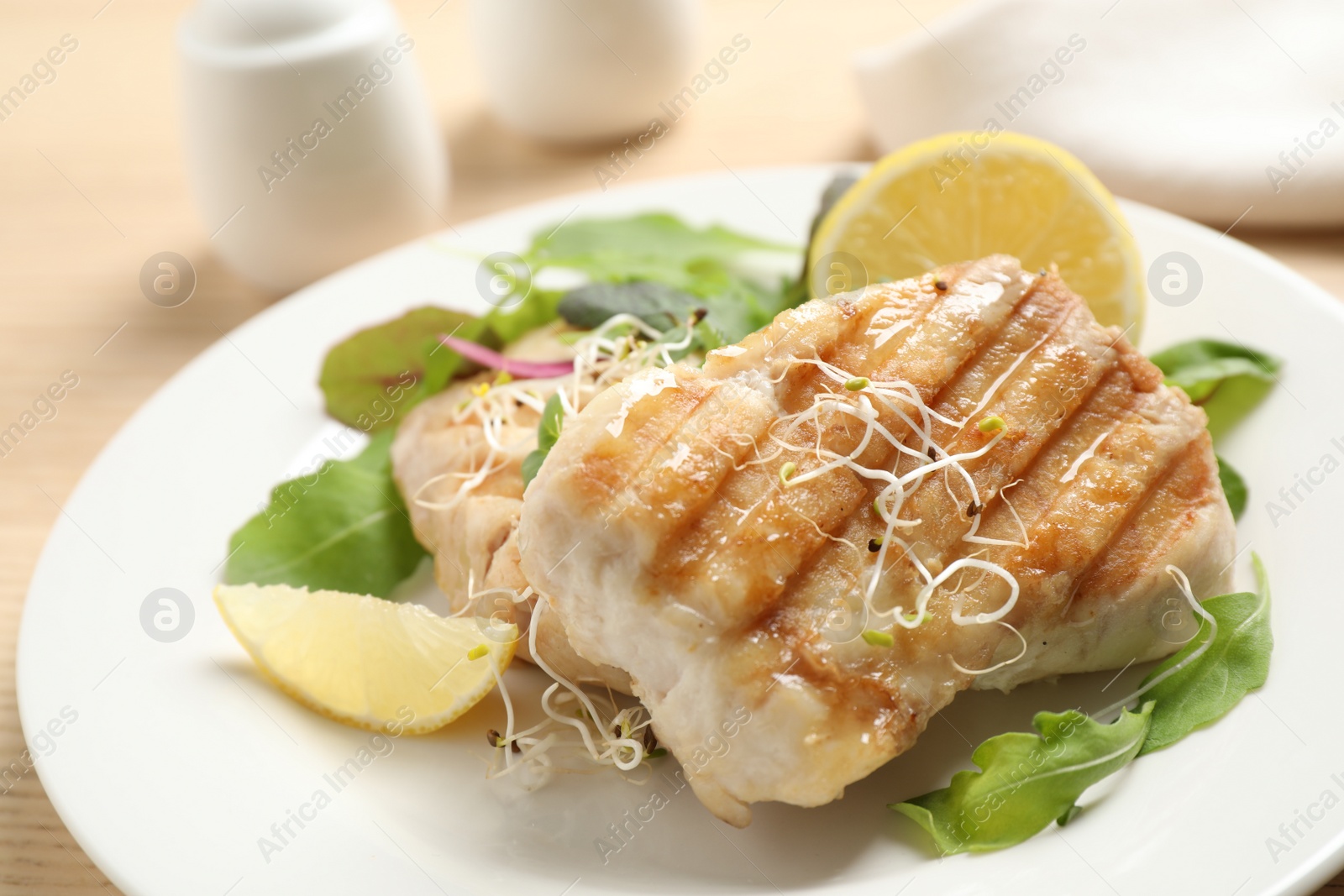 Photo of Tasty grilled fish with lemon served on table, closeup