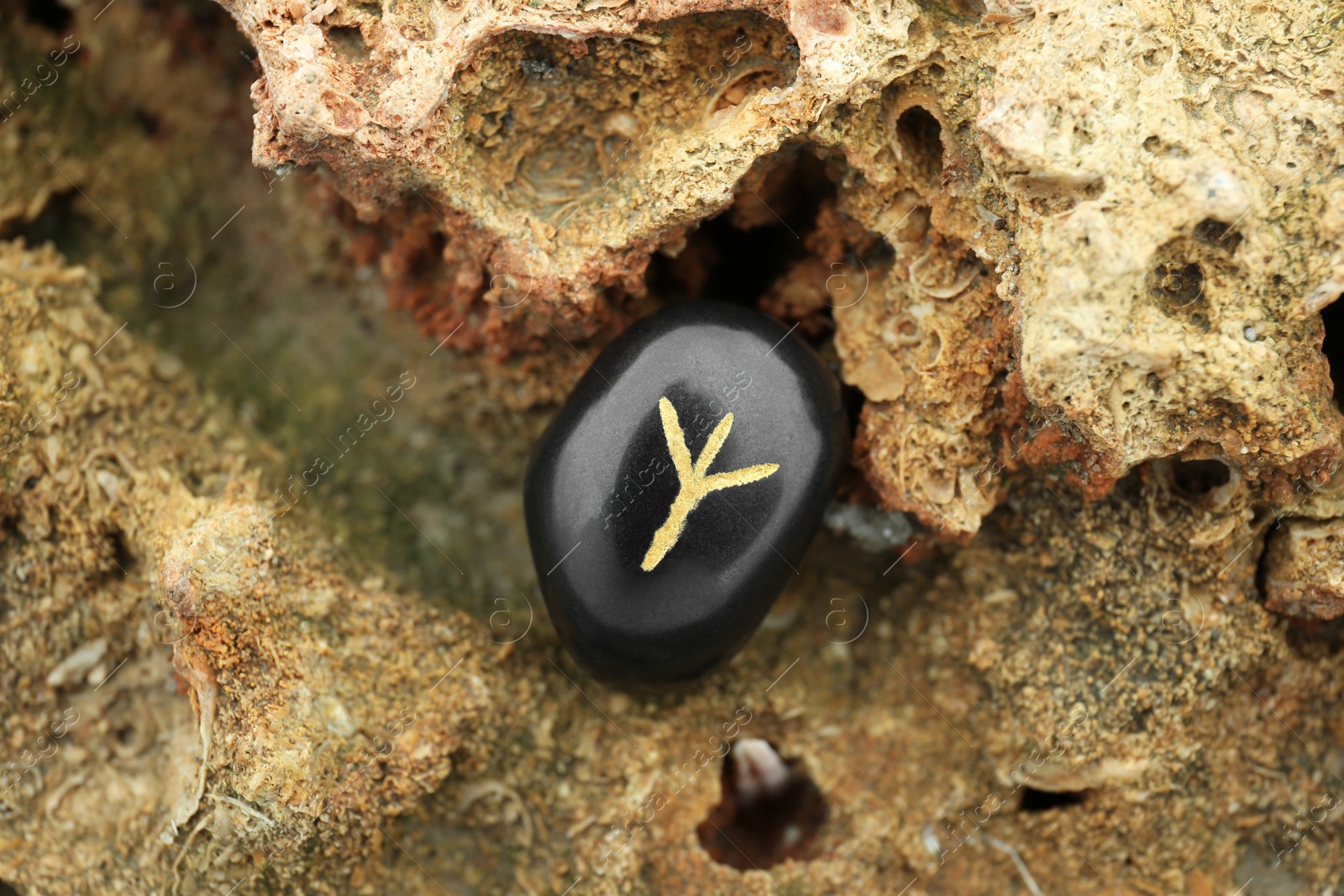 Photo of Black rune Algiz on stone outdoors, closeup