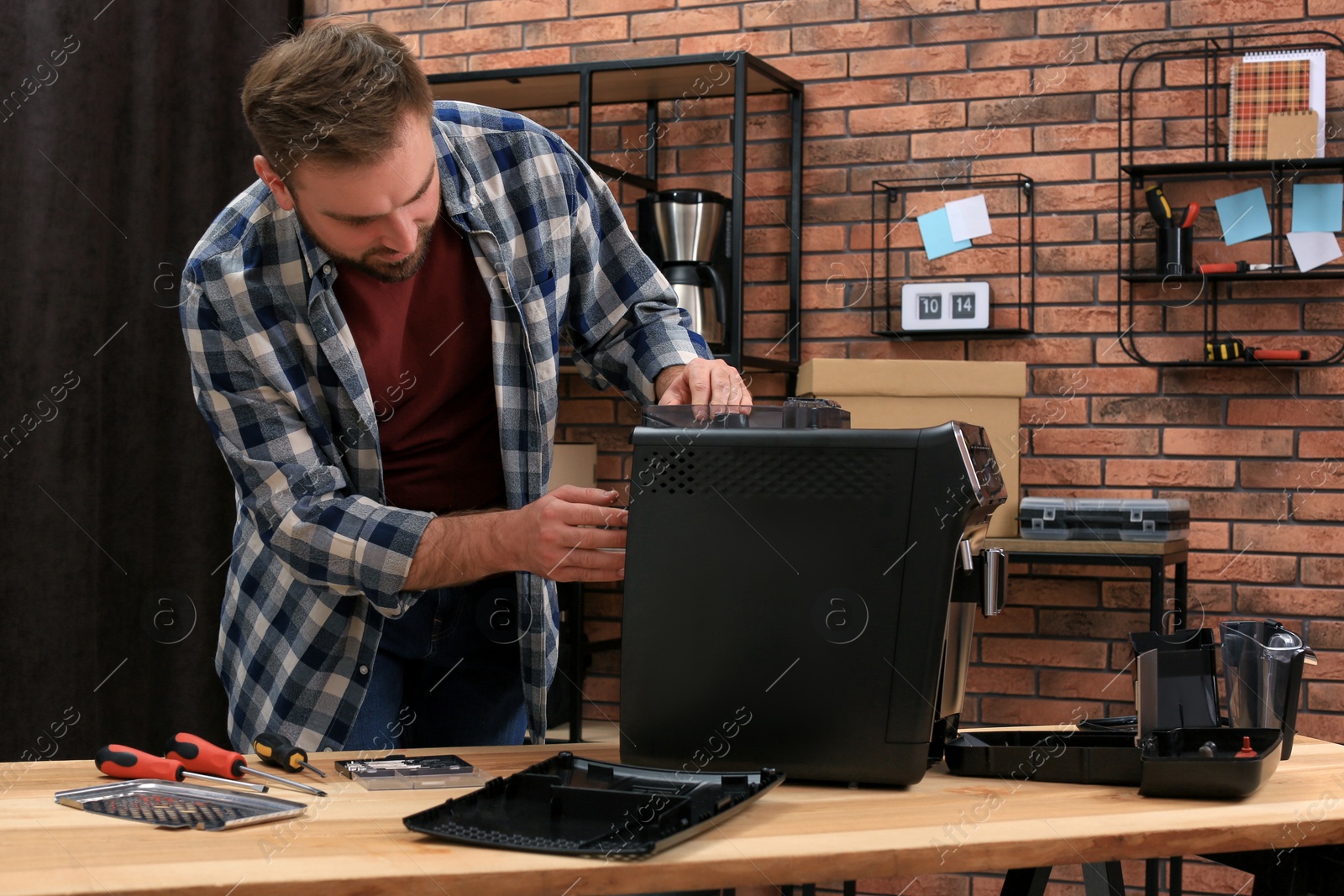 Photo of Man fixing coffee machine at table indoors