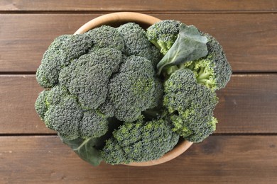 Bowl with fresh raw broccoli on wooden table, top view