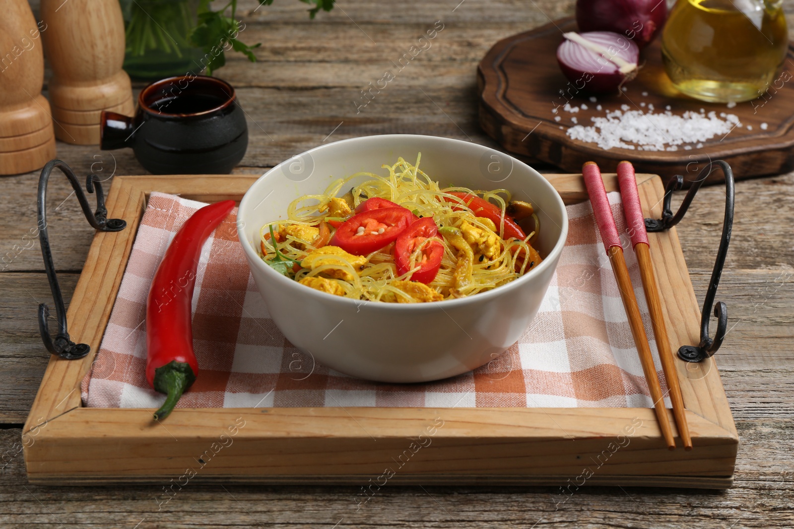 Photo of Stir-fry. Tasty noodles with vegetables and meat in bowl served on wooden table