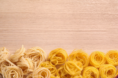 Photo of Different types of pasta on wooden table, flat lay. Space for text