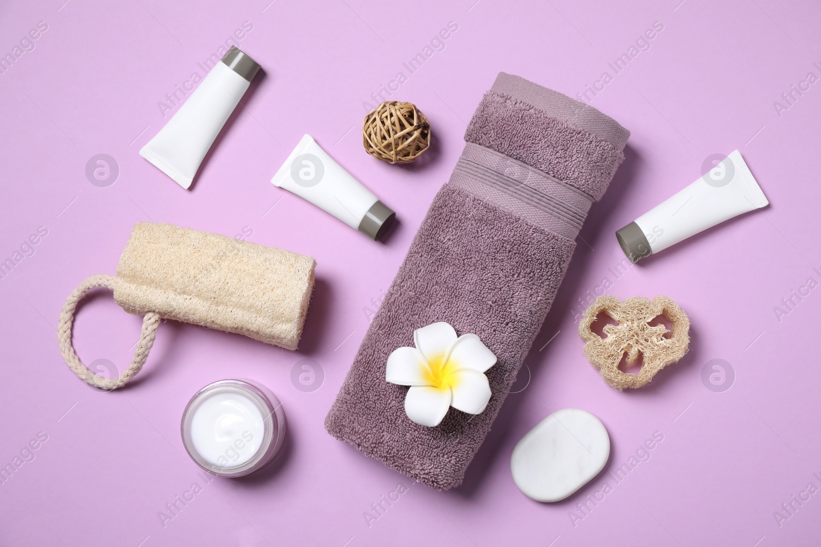 Photo of Flat lay composition with different cosmetic products and flower on lilac background