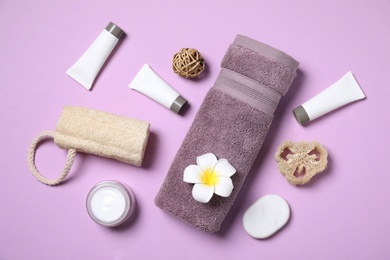 Photo of Flat lay composition with different cosmetic products and flower on lilac background