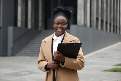 Photo of Happy woman with clipboard outdoors. Lawyer, businesswoman, accountant or manager