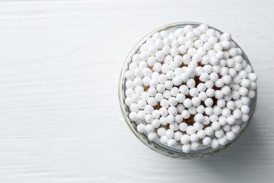 Photo of Many cotton buds in glass jar on white wooden table, top view. Space for text