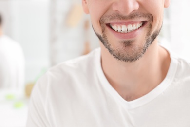 Photo of Young man with beautiful smile indoors. Teeth whitening